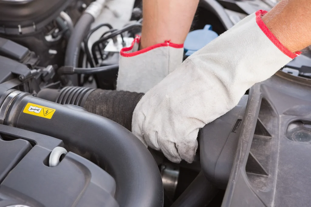 Main contrôlant une durite d’admission dans le compartiment moteur d’un Peugeot Expert 2.0 HDi 120