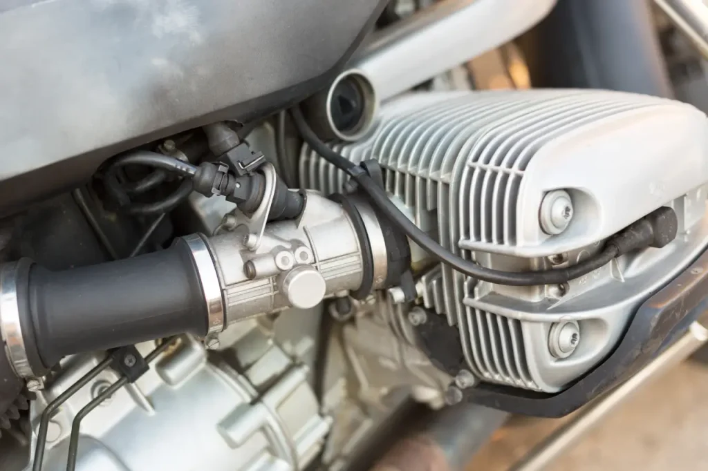 Vue rapprochée de l’admission et du carburateur sur un moteur 2 temps de moto.